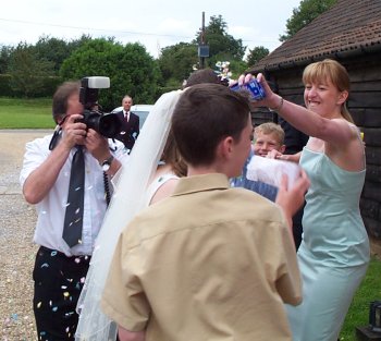 Excited guests tip confetti on the happy couple (both obscured, sorry)